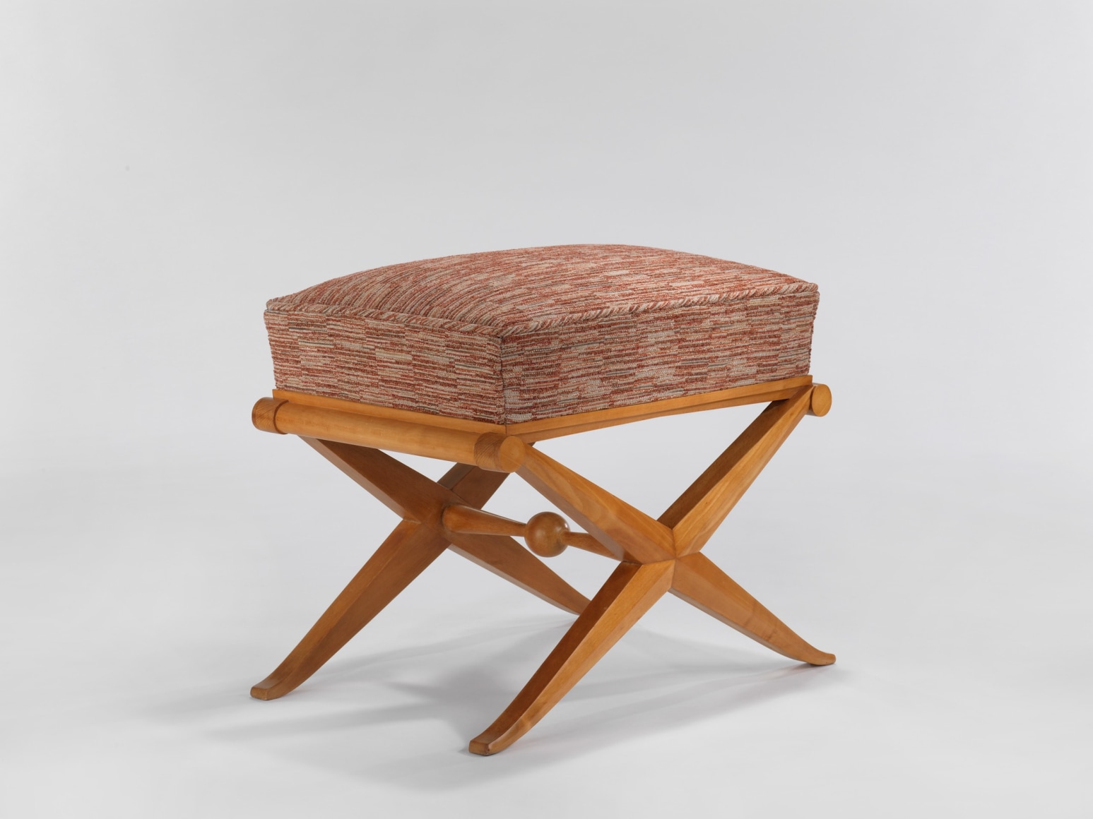 Wooden stool with a fabric seat in front a white background