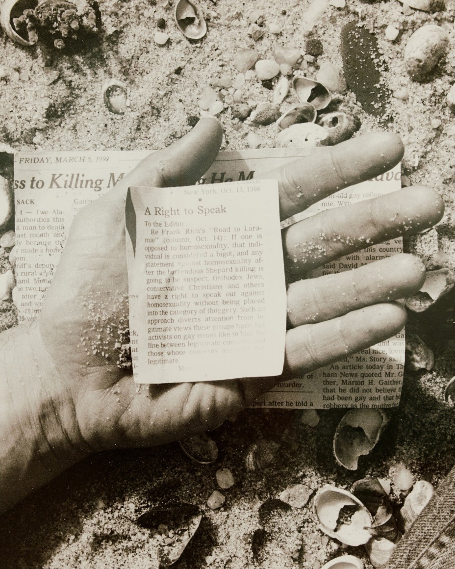 black and white photograph of newspaper clipping in a hand