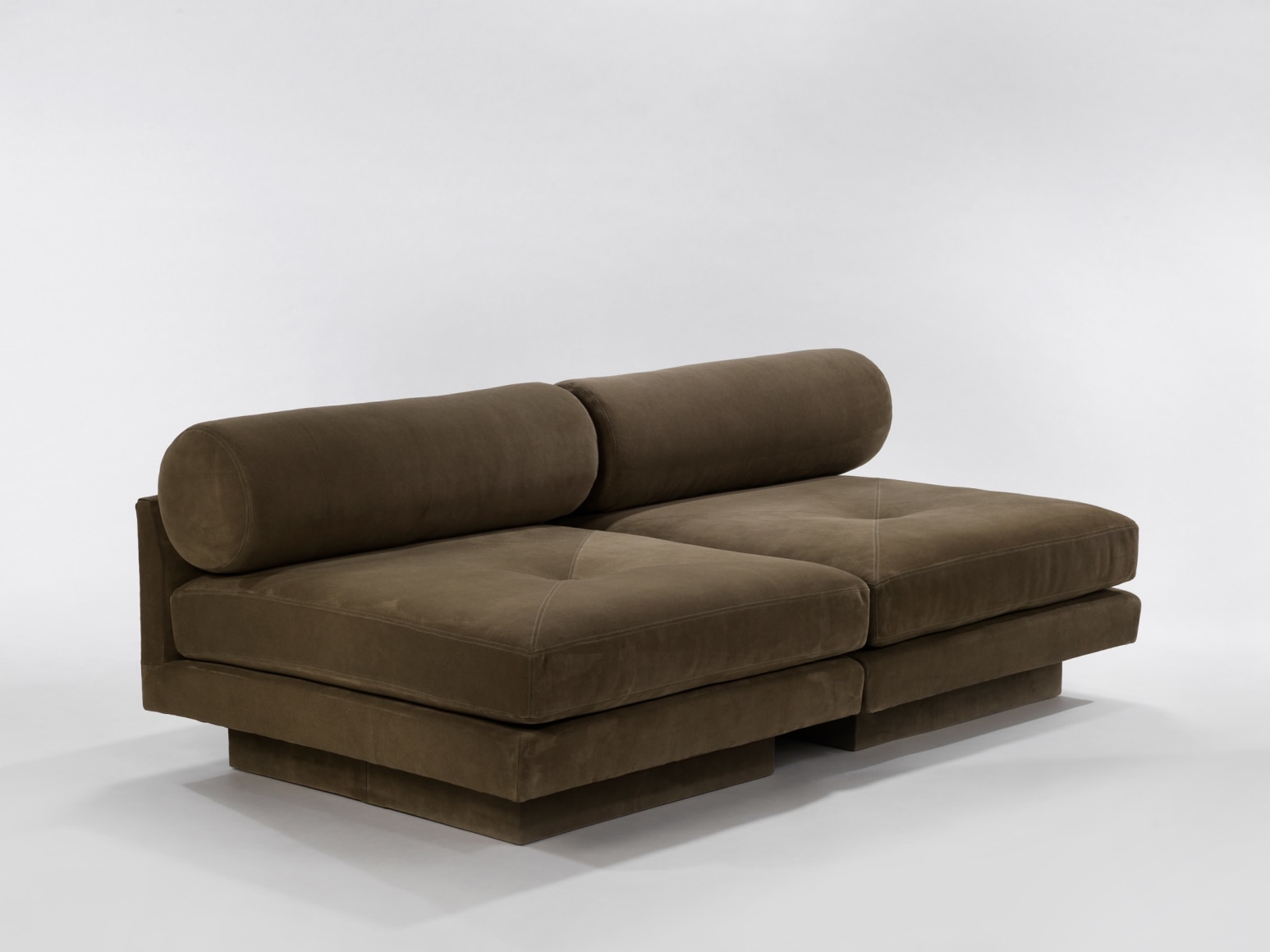 Deep seated upholstered chairs with round bolster pillows together as a sofa