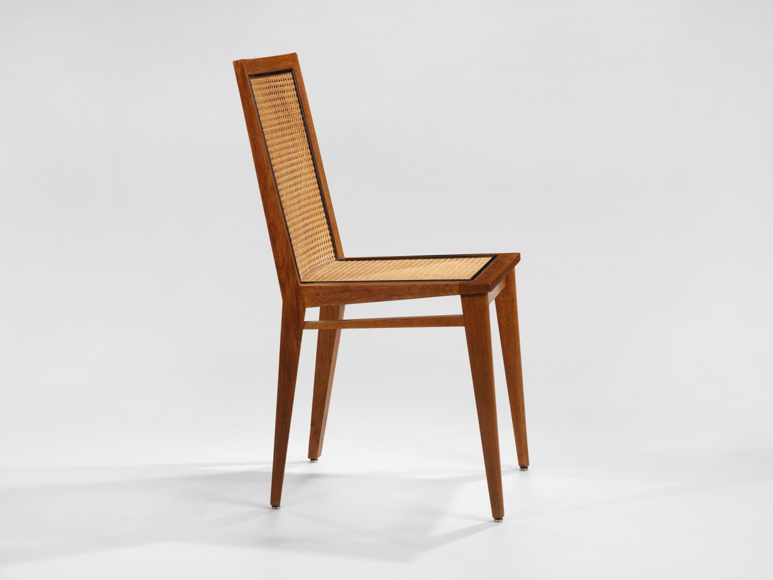 photograph of 4 wood chairs around a wood dining table in a blank room