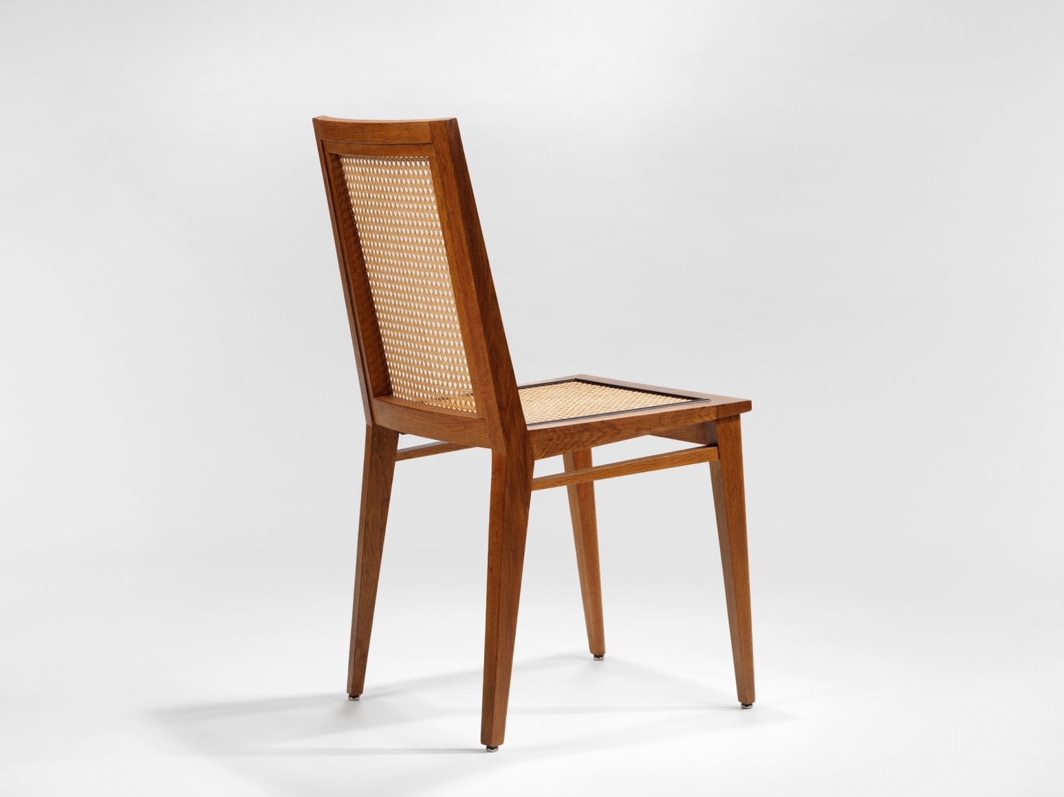 photograph of 4 wood chairs around a wood dining table in a blank room