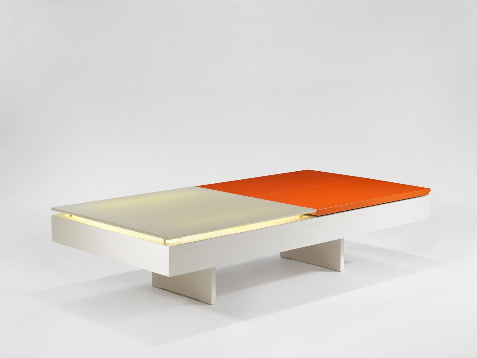 photograph of low table by Motte in a blank room, top of table is half orange and half white