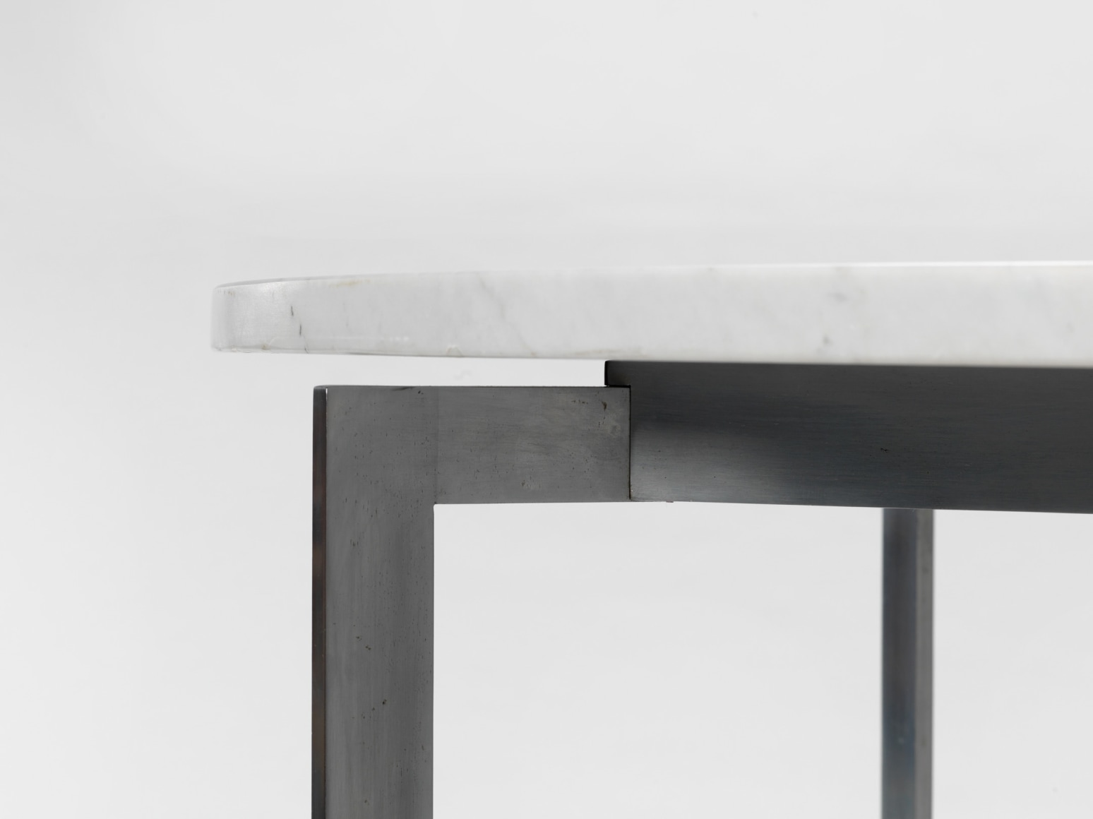 photograph of a table with steel legs and a marble top in a blank room