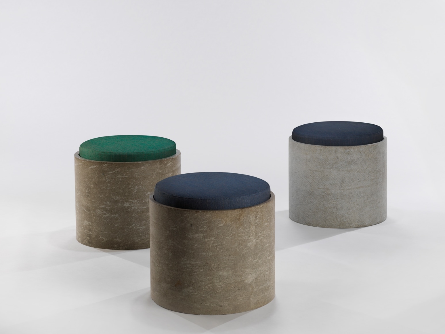 Set of three low concrete stools with cushions