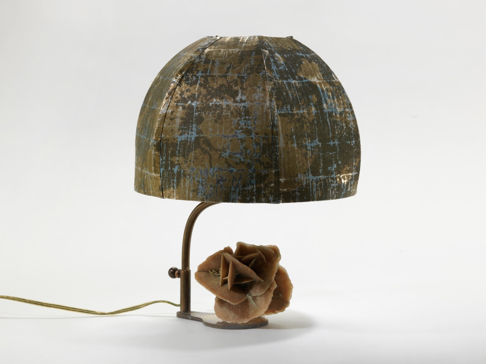 photograph of a lamp with a round shade and a sculpture of a rose at its base