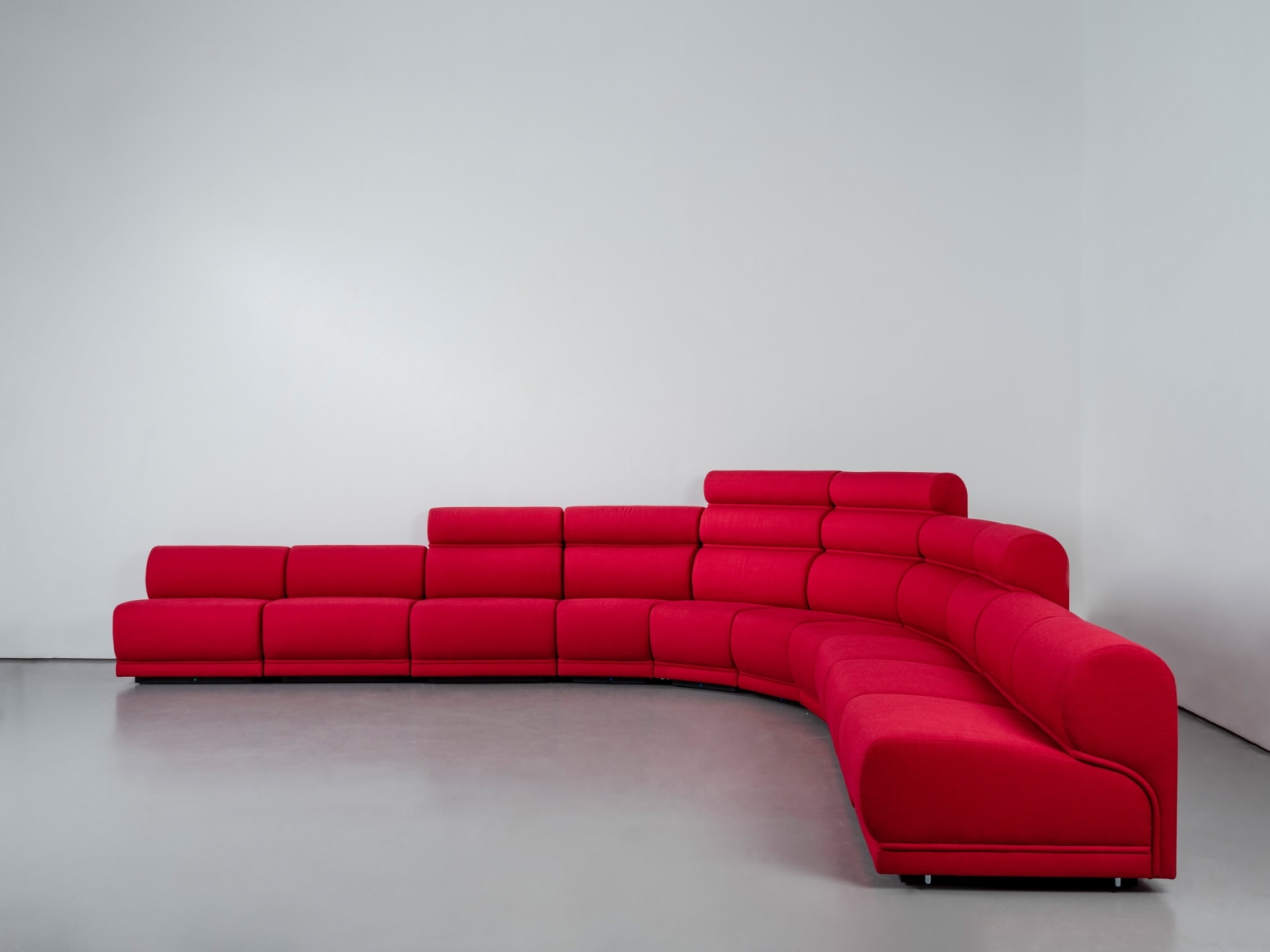 Red long huge sofa upholstered photo shots in a studio. Sofa is by Pierre Paulin.