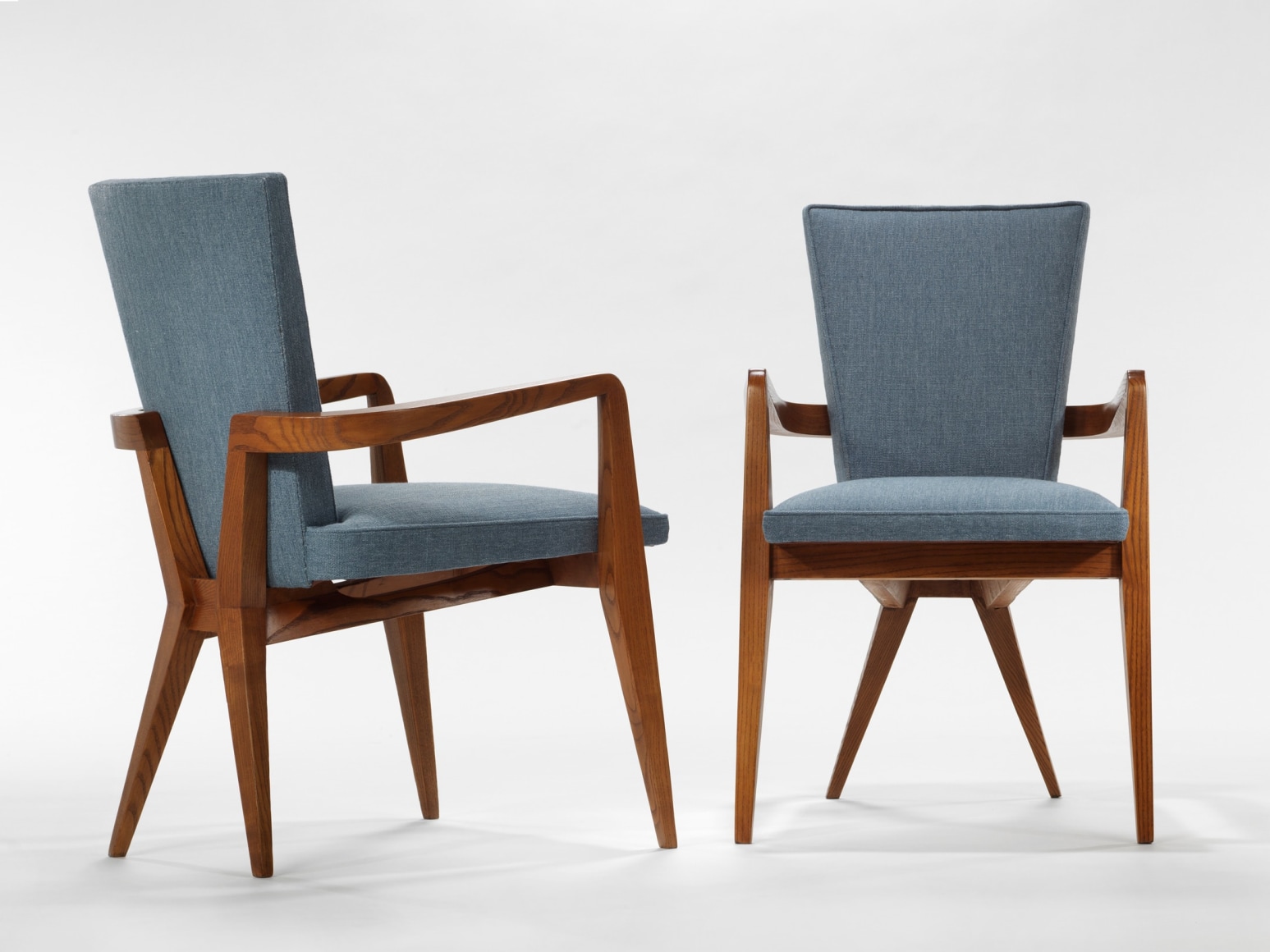 photograph of chair in a blank room with wooden legs and blue upholstery