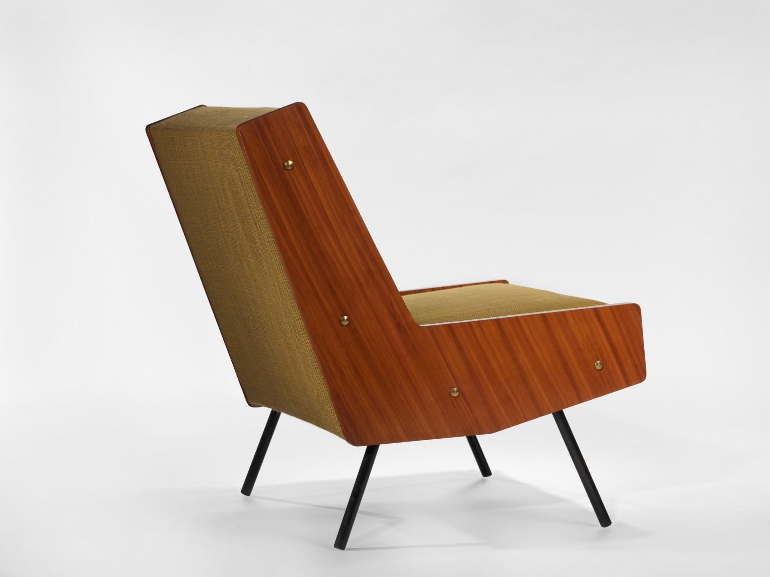 photograph of chair by Motte in a blank room, chair is made of painted metal, mahogany, and fabric