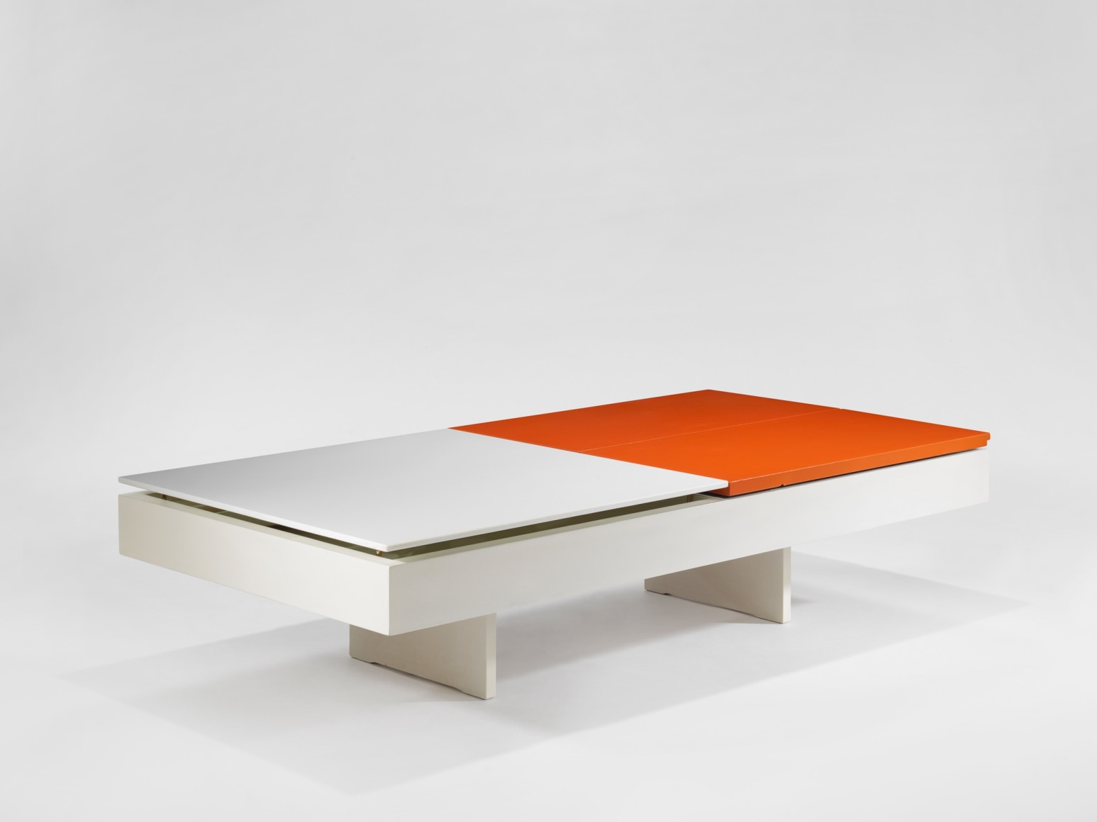 photograph of low table by Motte in a blank room, top of table is half orange and half white