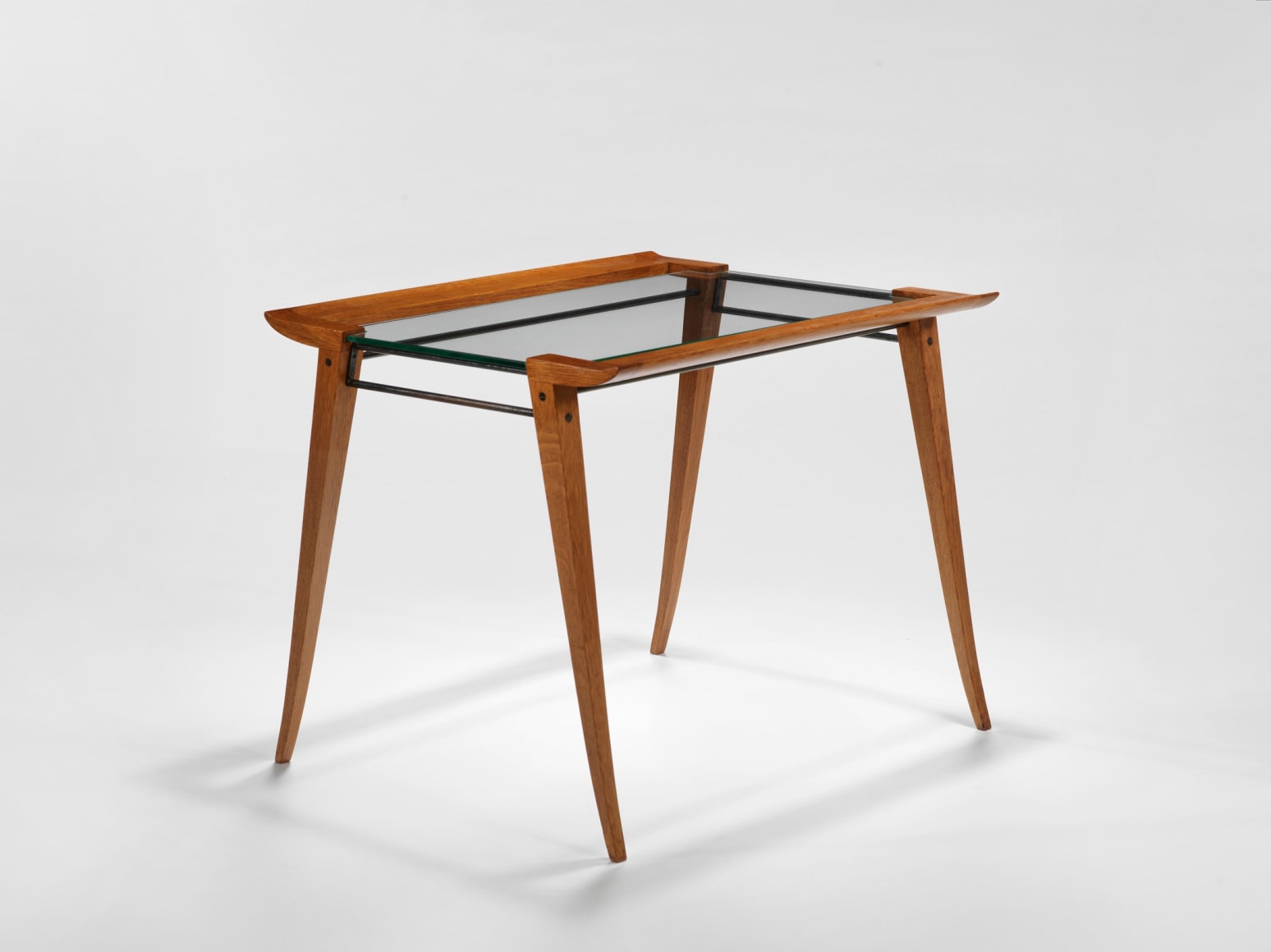 photograph of a set of three nesting tables, legs are made from wood and tops surface is glass