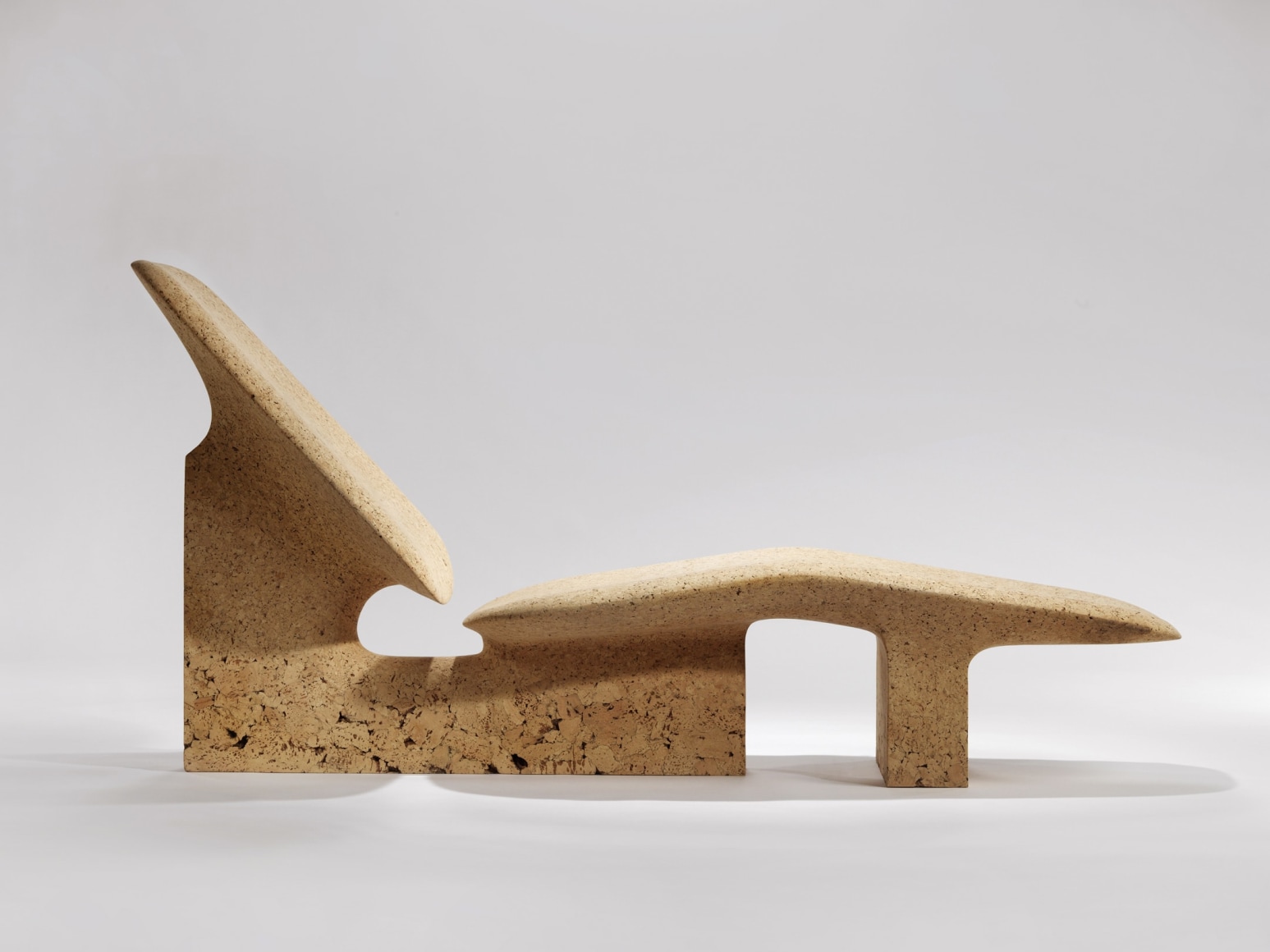 chaise longue in burnt cork On a plain grey background.