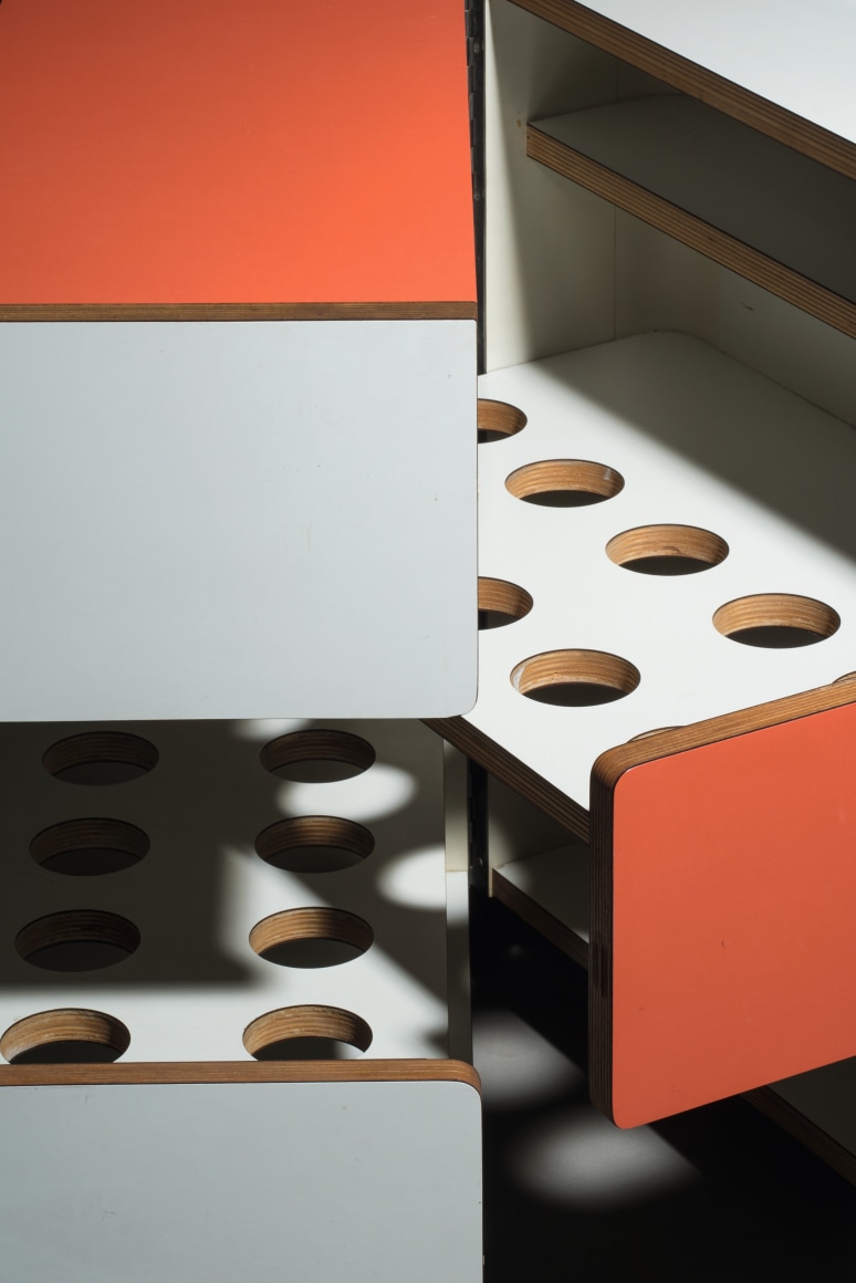 Bar cart in orange and white shown open and closed with different holes for various parts.