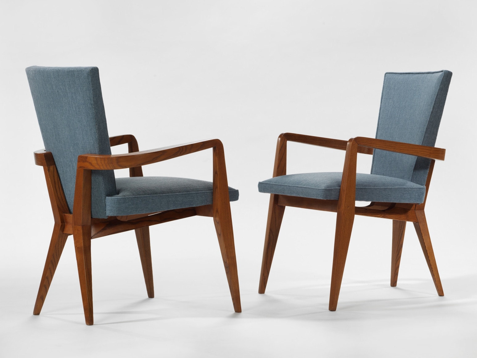 photograph of chair in a blank room with wooden legs and blue upholstery