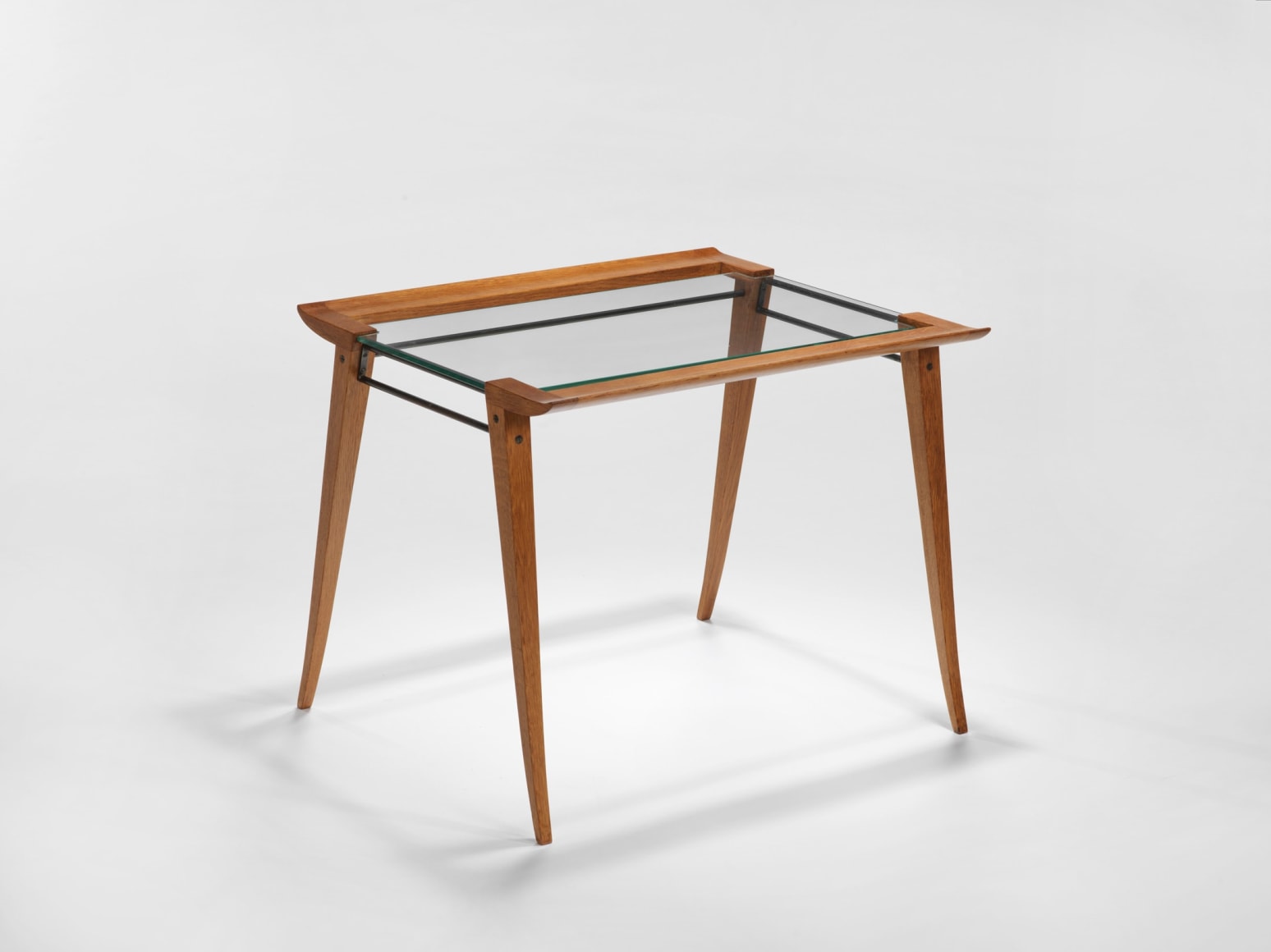 photograph of a set of three nesting tables, legs are made from wood and tops surface is glass