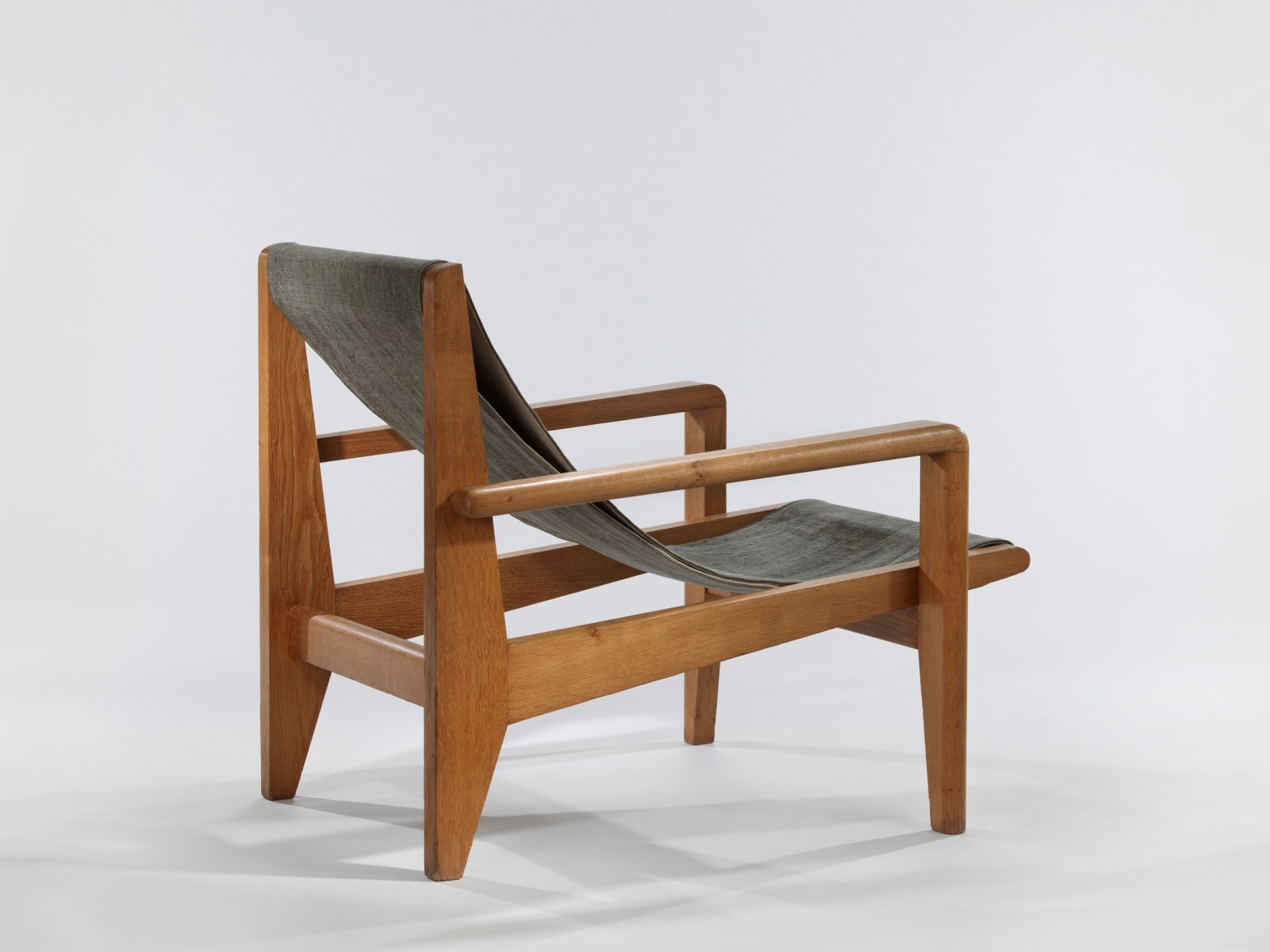 Back view of low wood armchairs with canvas sling seat
