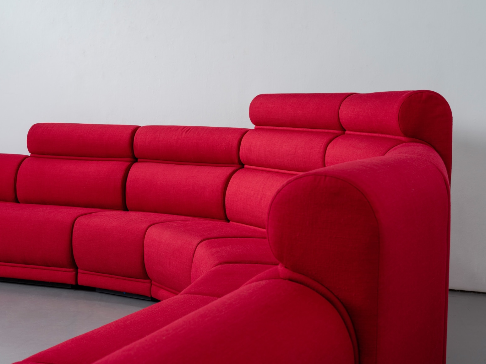 Red long huge sofa upholstered photo shots in a studio. Sofa is by Pierre Paulin.