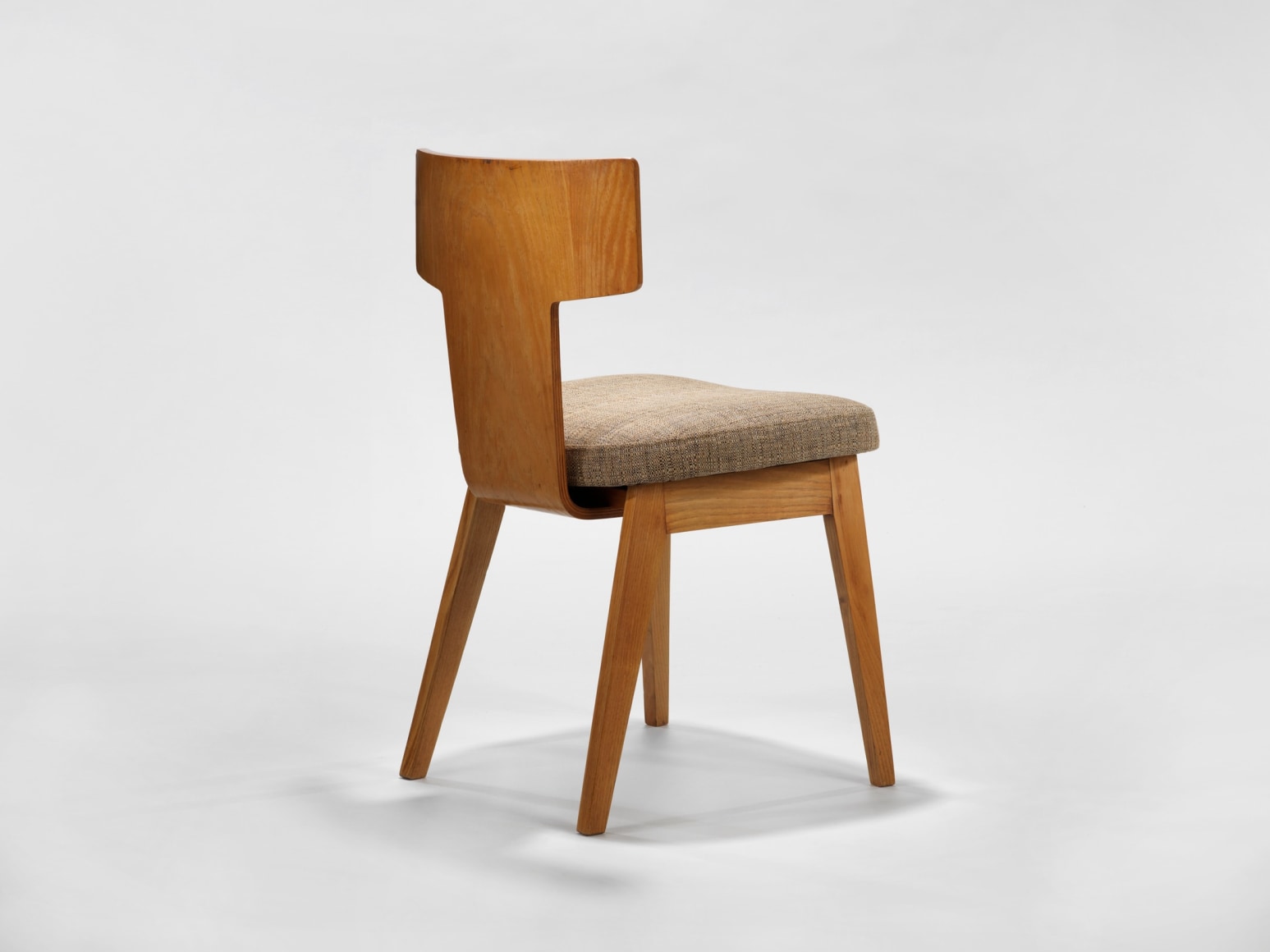 photograph of a chair with beige apholstery in a blank room