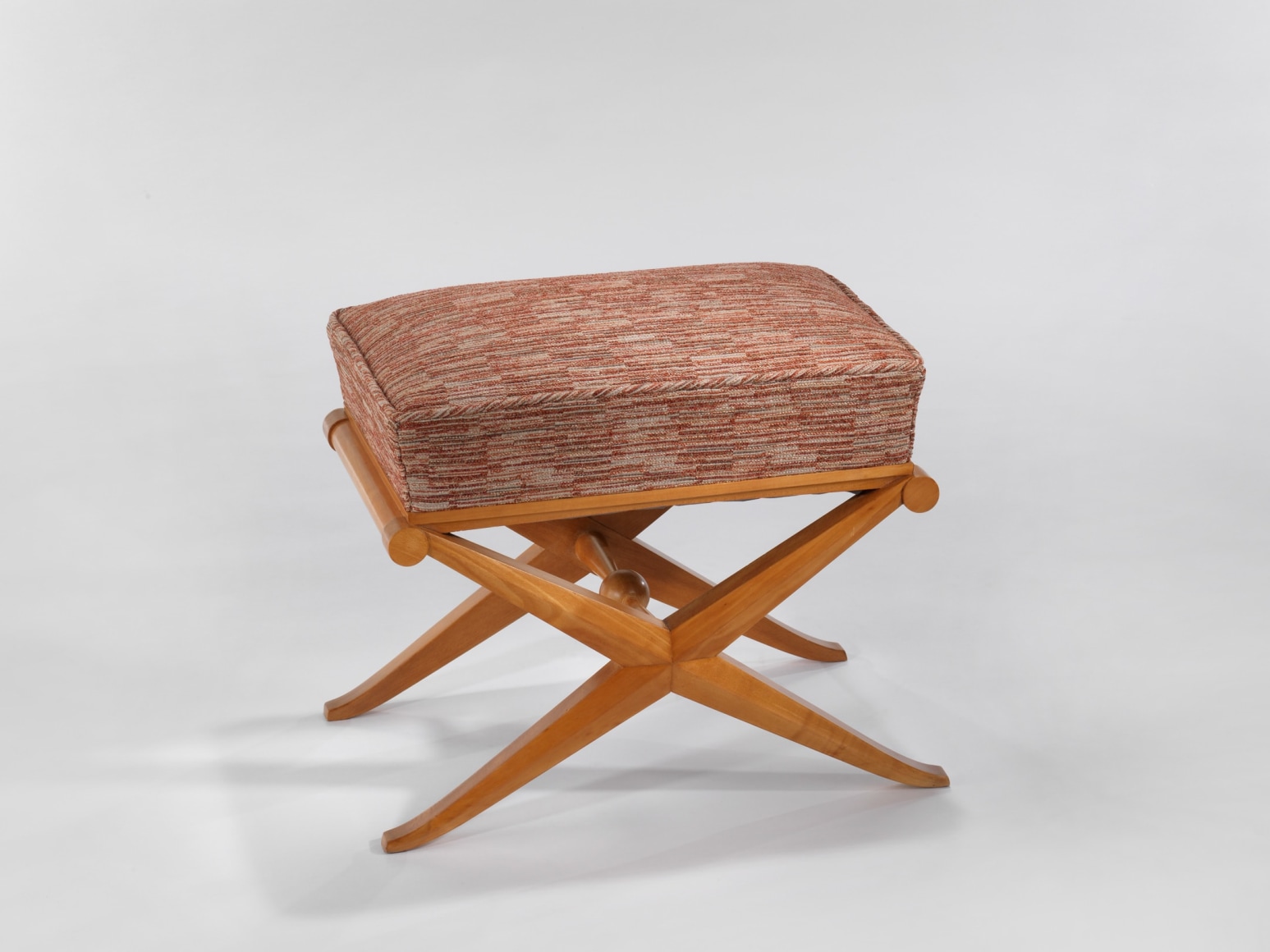 Wooden stool with a fabric seat in front a white background