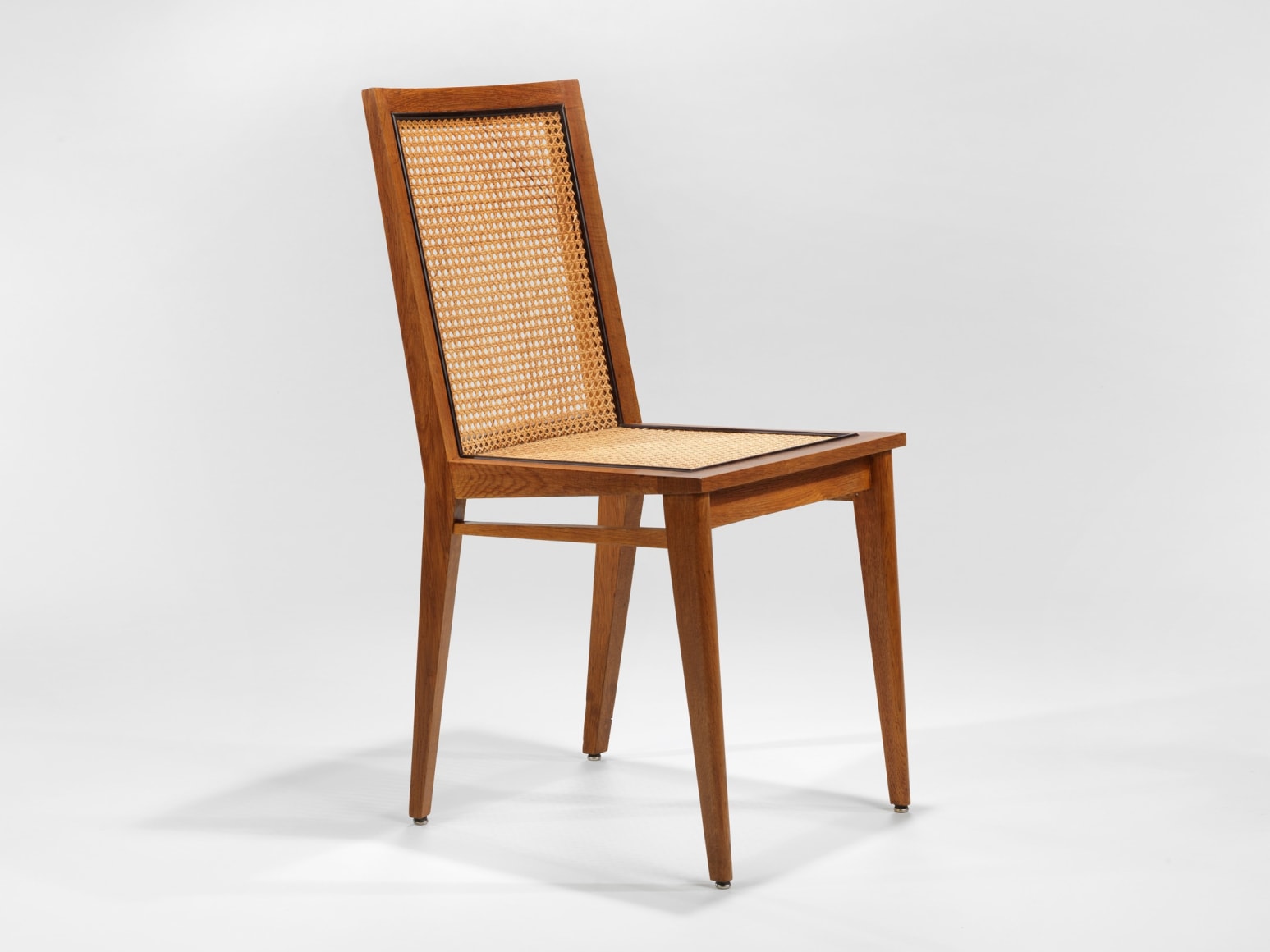 photograph of 4 wood chairs around a wood dining table in a blank room