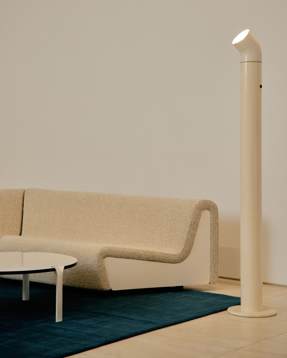 Low upholstered sofa with tubular floor lamp