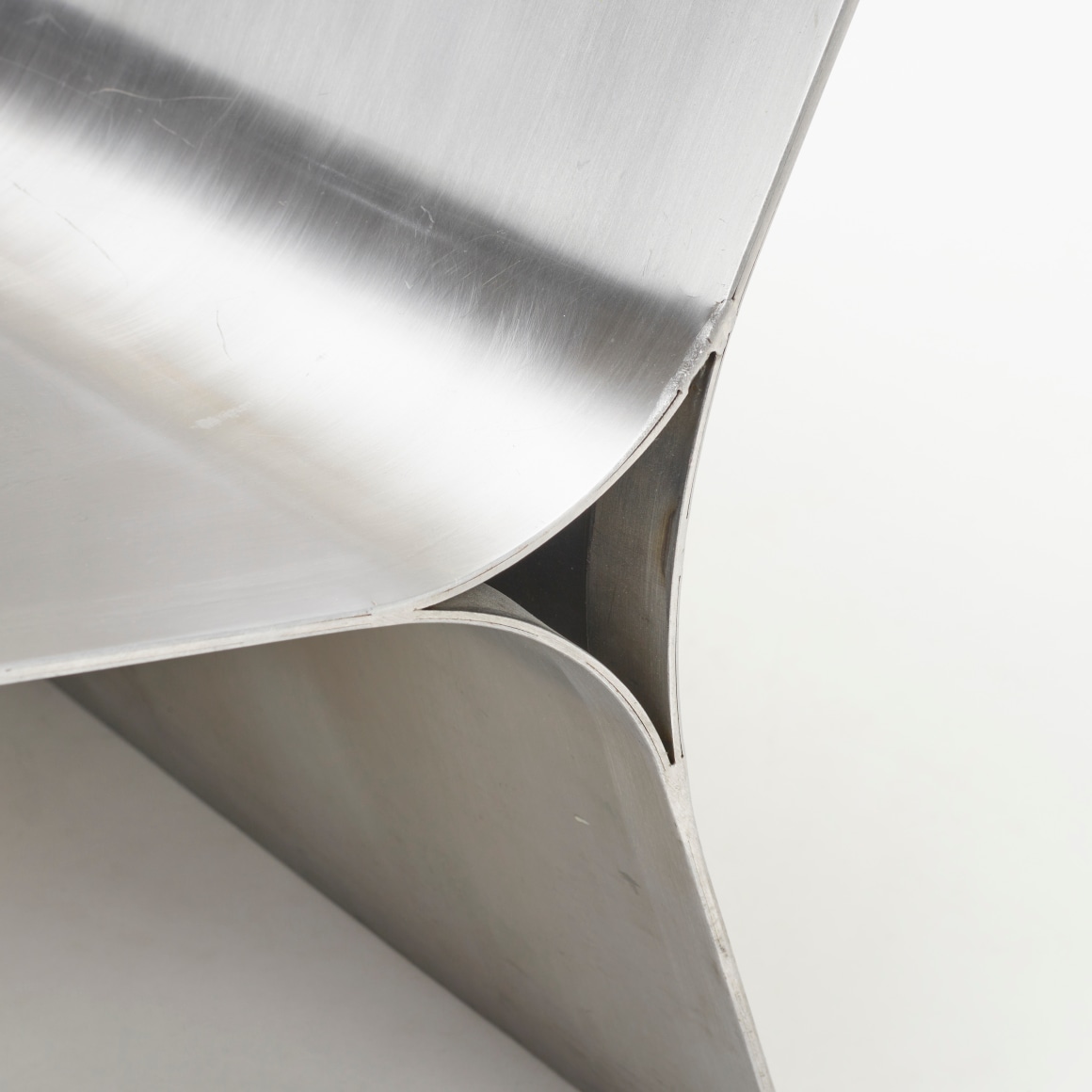 Folded chair by Maria Pergay in steel. Shot of chair from front on where you can see the corner of the chair.