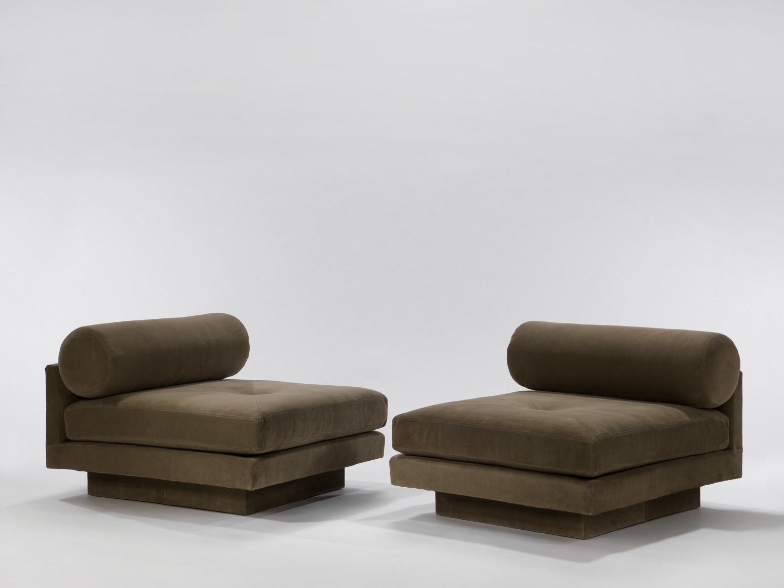 Deep seated upholstered chairs with round bolster pillow facing each other