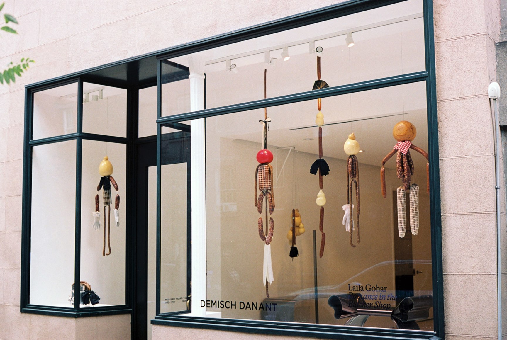 Levitating saucissons and scamorza of varied shapes and sizes form puppet like figures in the window. Photo by Adrianna Glaviano