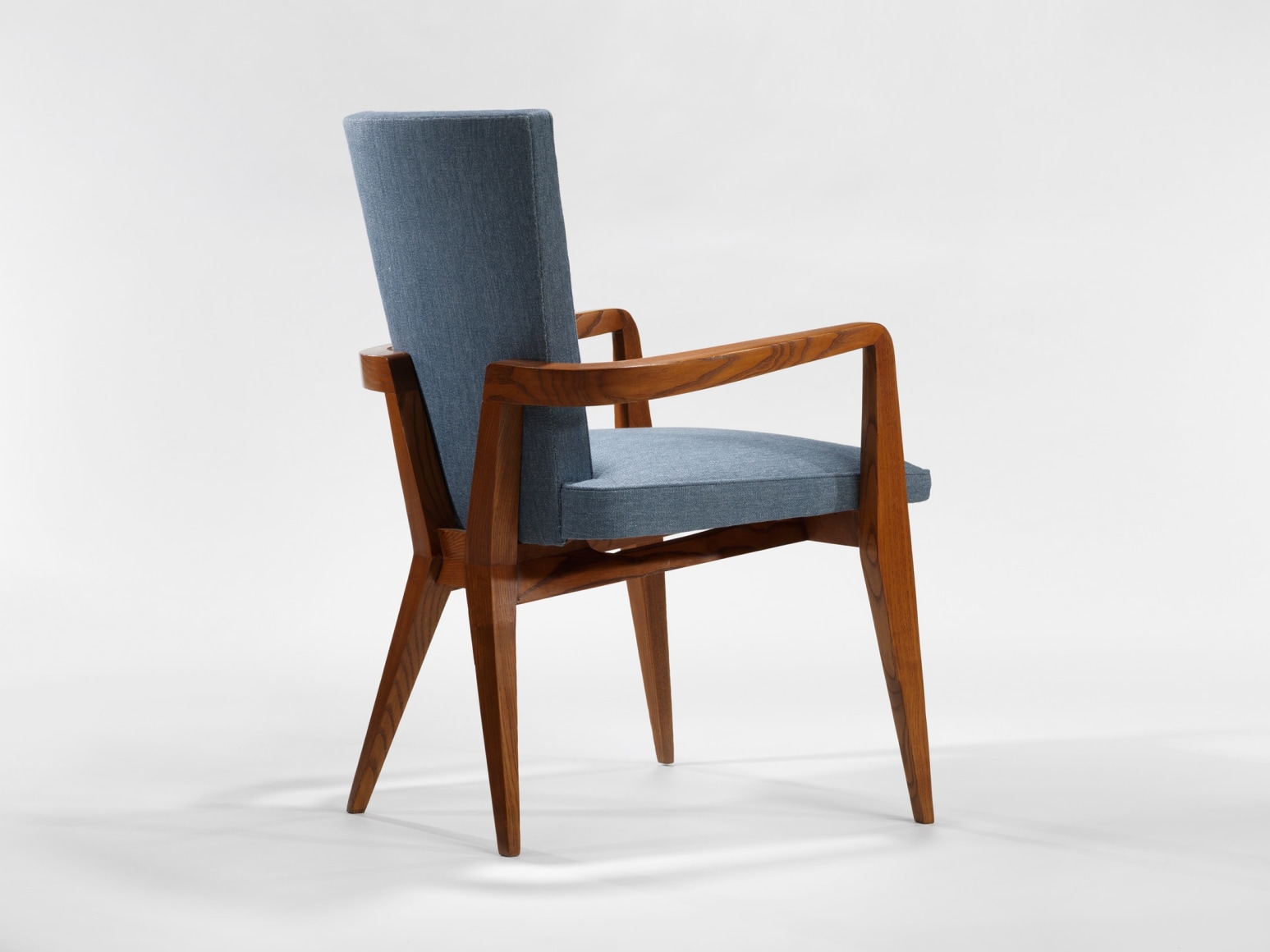 photograph of chair in a blank room with wooden legs and blue upholstery
