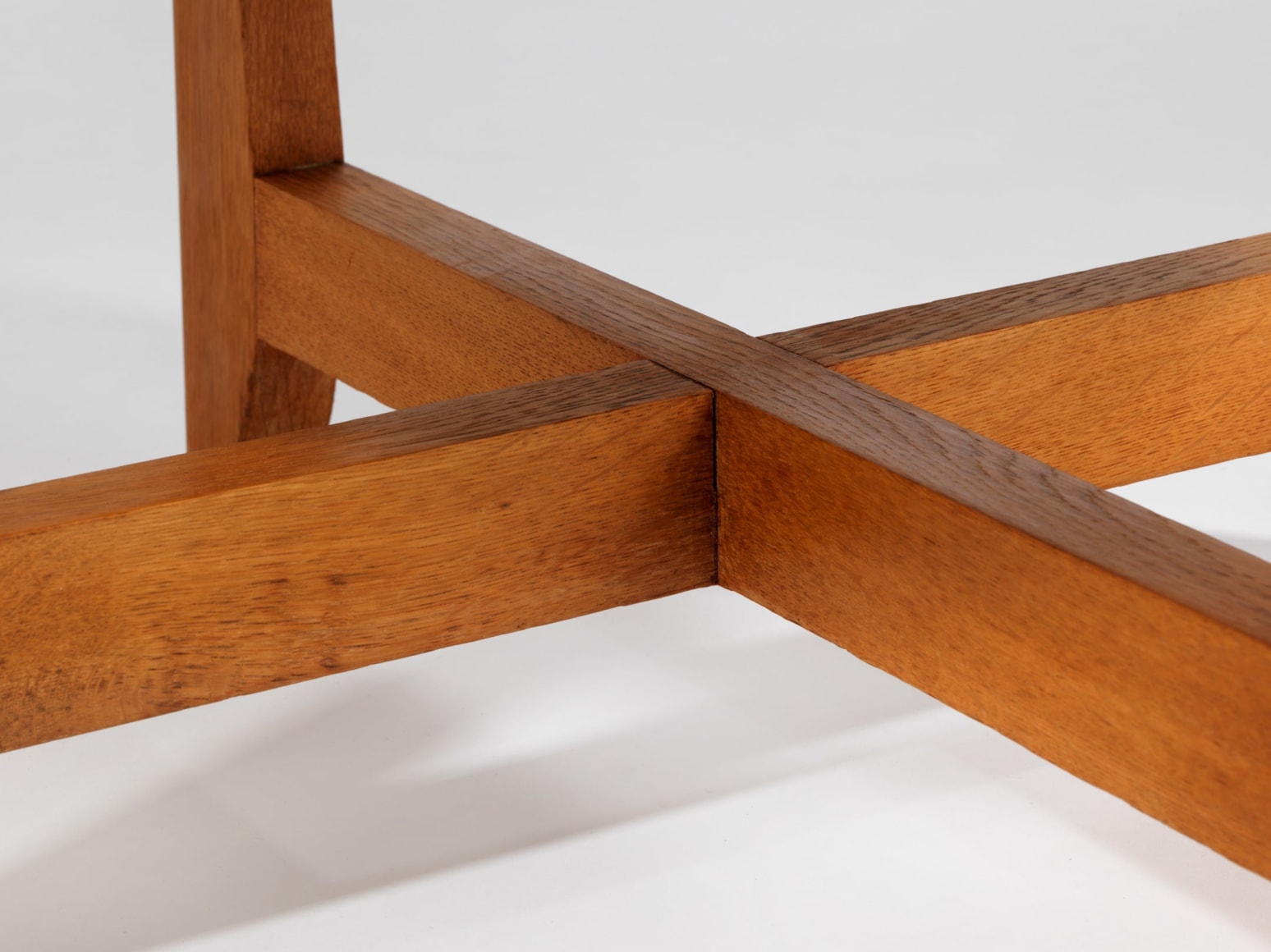 Wooden table with cross base and glass top by Renou and Genniset. View from close up.