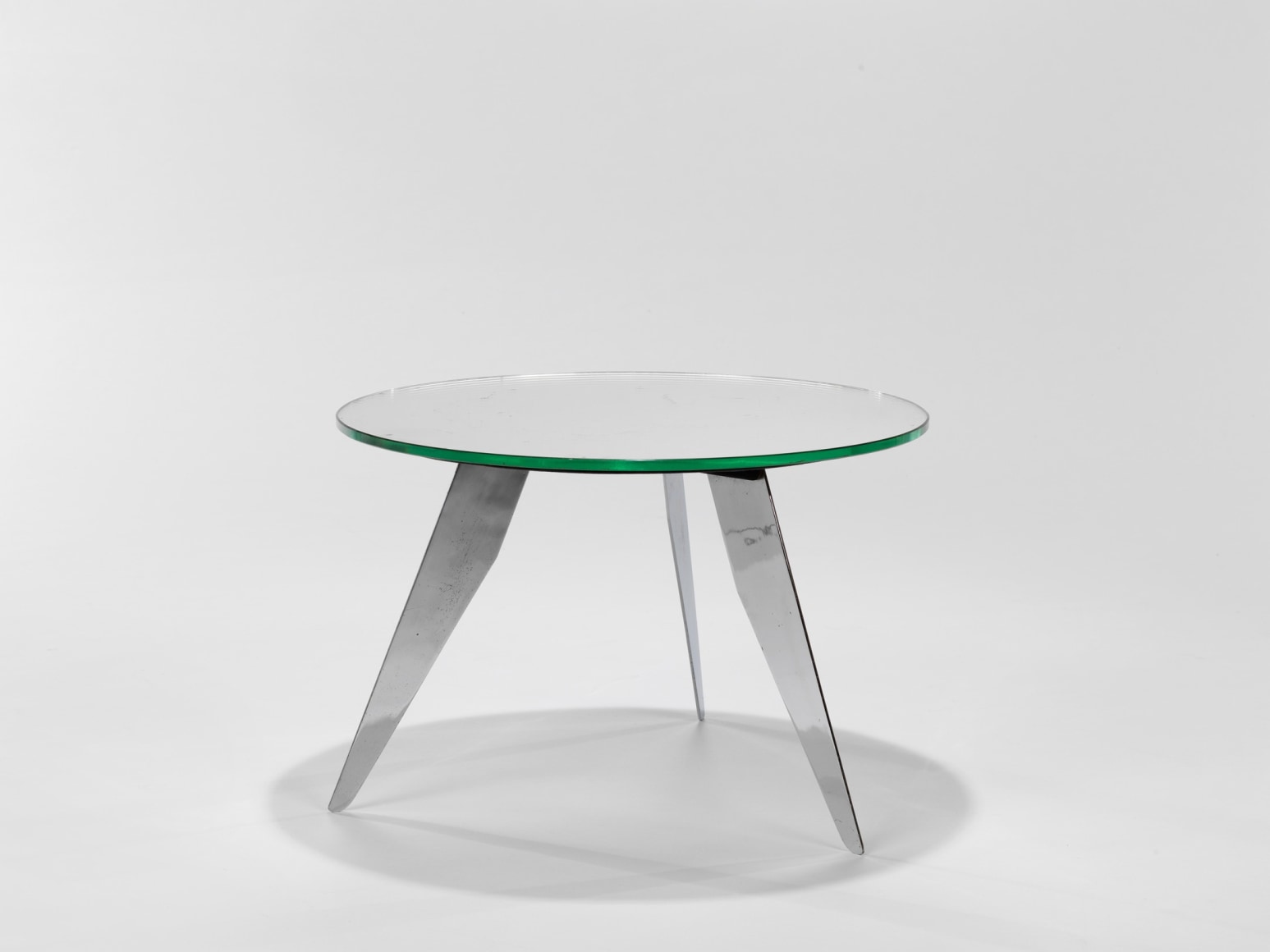 photograph of table in a blank room with metal legs and a glass top