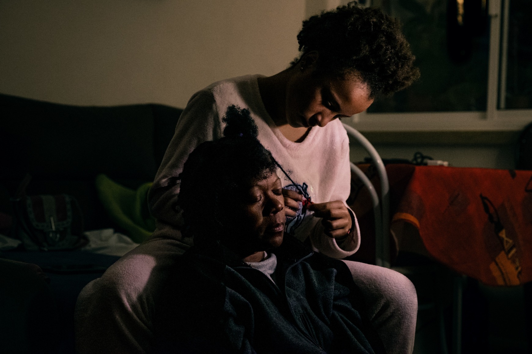 Ana Maria Jeremias's granddaughter, Leonor, unbraiding her grandmother's hair at her home in Rio de Mouro. Lisbon, Portugal, 2024