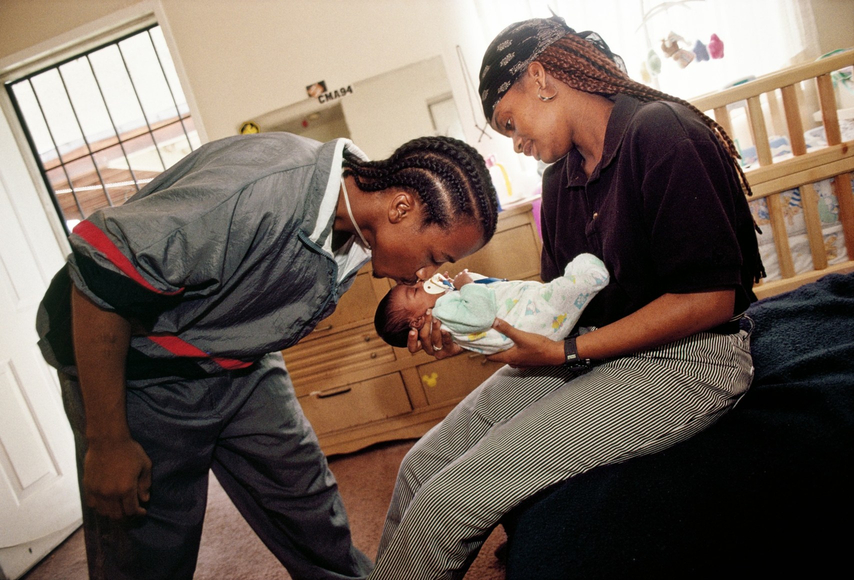 Ozzie and his girlfriend, Chantel, both 17, live together with their newborn and Ozzie’s mother, South Central Los Angeles, 1995, Archival Pigment Print