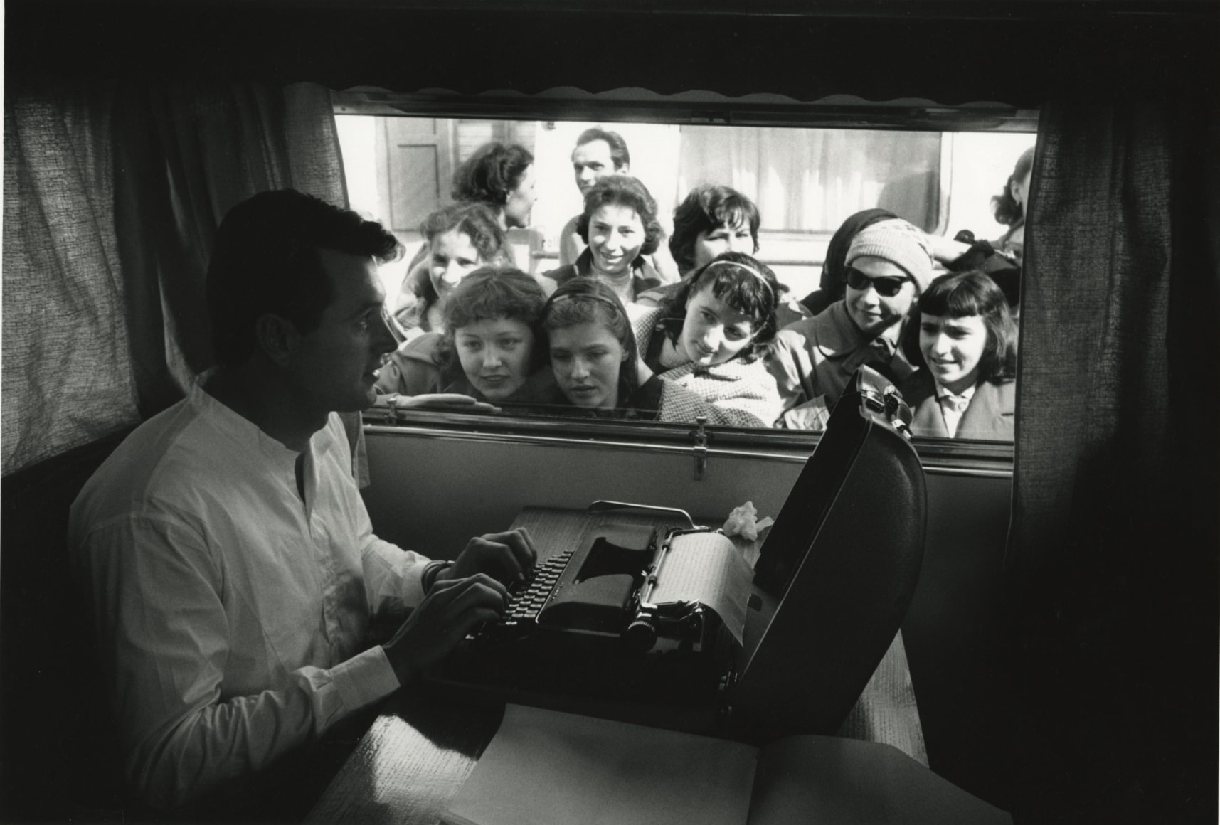 Rock Hudson trying to type in his trailer, but the fans are a bit distracting, on location in Italy for "Farewell To Arms", 1957, Archival Pigment Print