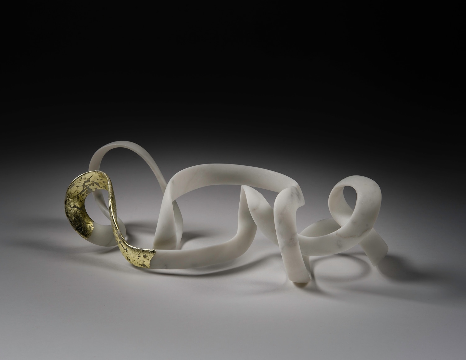 a sculpture by Elizabeth Turk of a thin looping bands of marble, a corner of which is covered in gold leaf