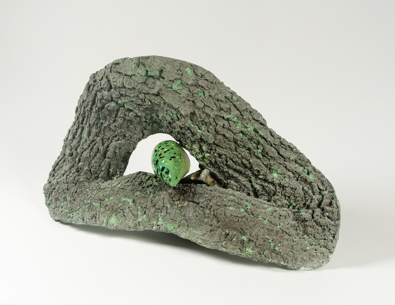 a sculpture by Lily Cox-Richard of cast tree bark with a green tongue-like form emerging from a knot in the center
