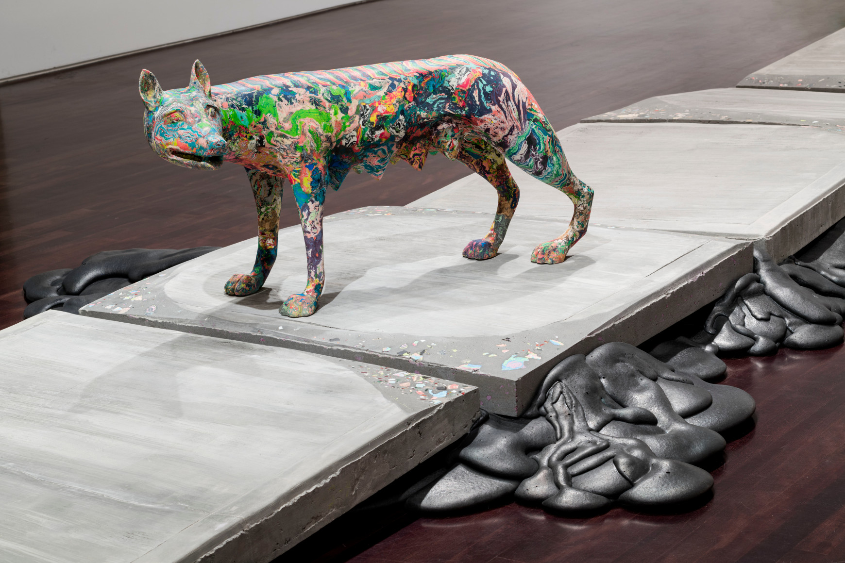 a sculpture by Lily Cox-Richard of a multi-colored Roman She-wolf standing on a concerete sidewalk