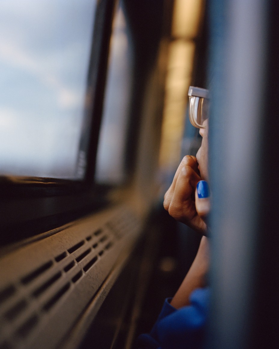 Side of face of person looking out train window photographed from behind, by McNair Evans