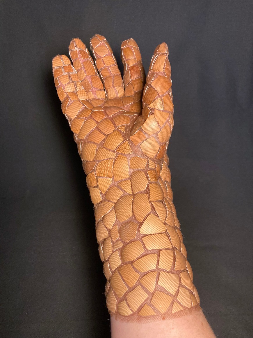 A work style glove made from fragments of brown egg shells which highlights the fragility of the medium