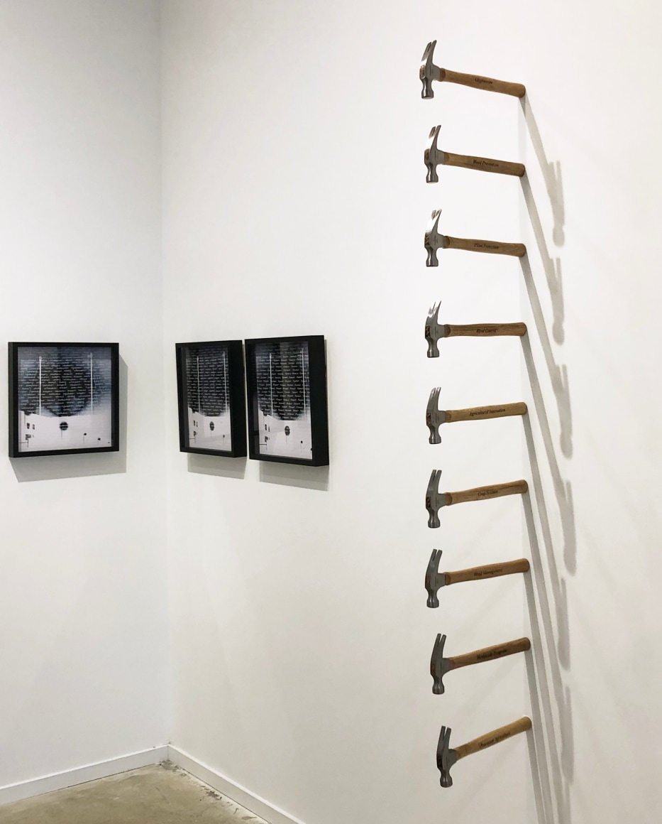 Wall installation of hammers engraved with text