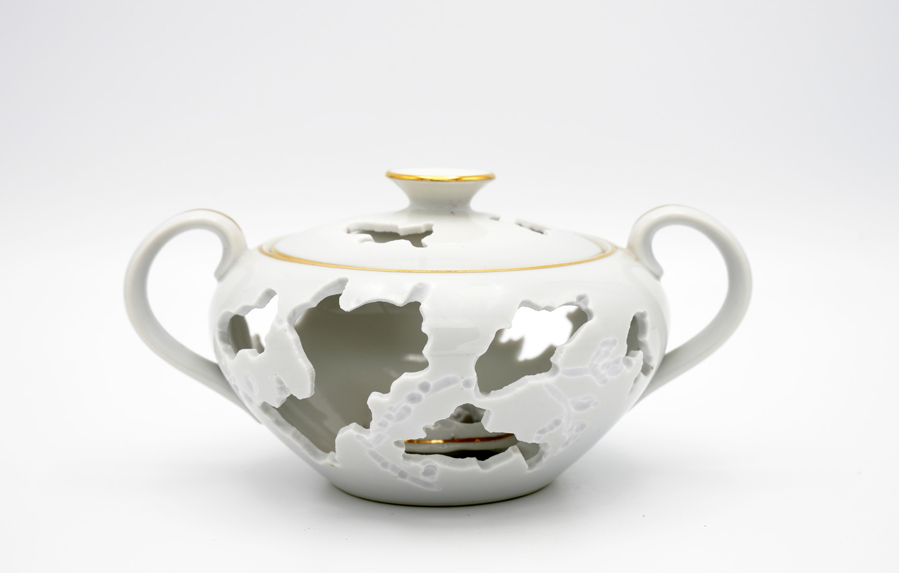 A gold rimmed porcelain sugar bowl with hand cut patterns