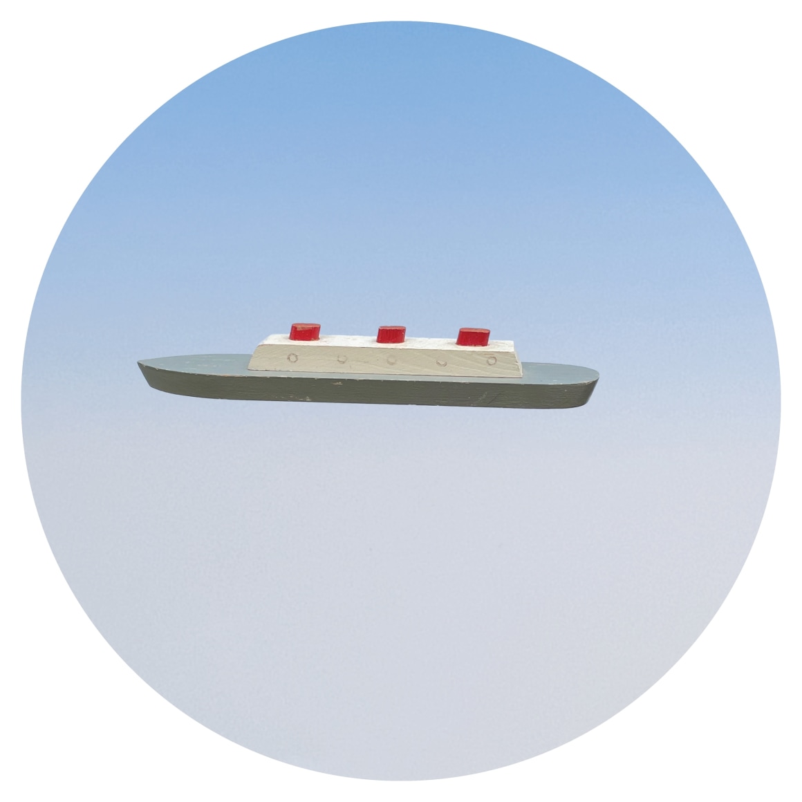 Circular image of toy boat on blue background, by Workingman Collective