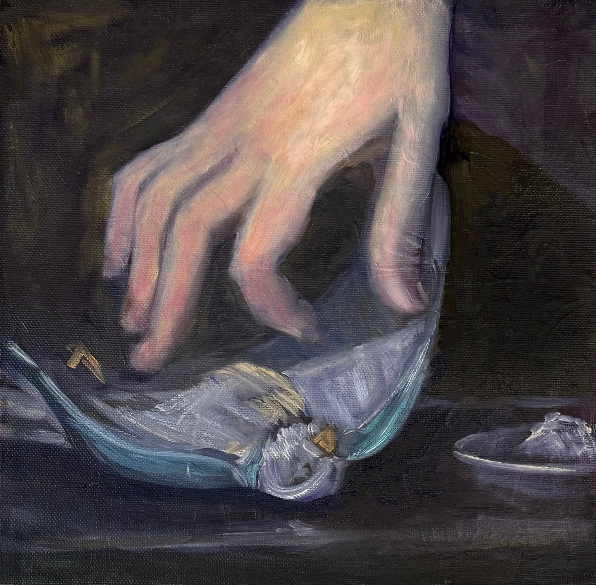 a female hand reaches for a dead bird on a table top