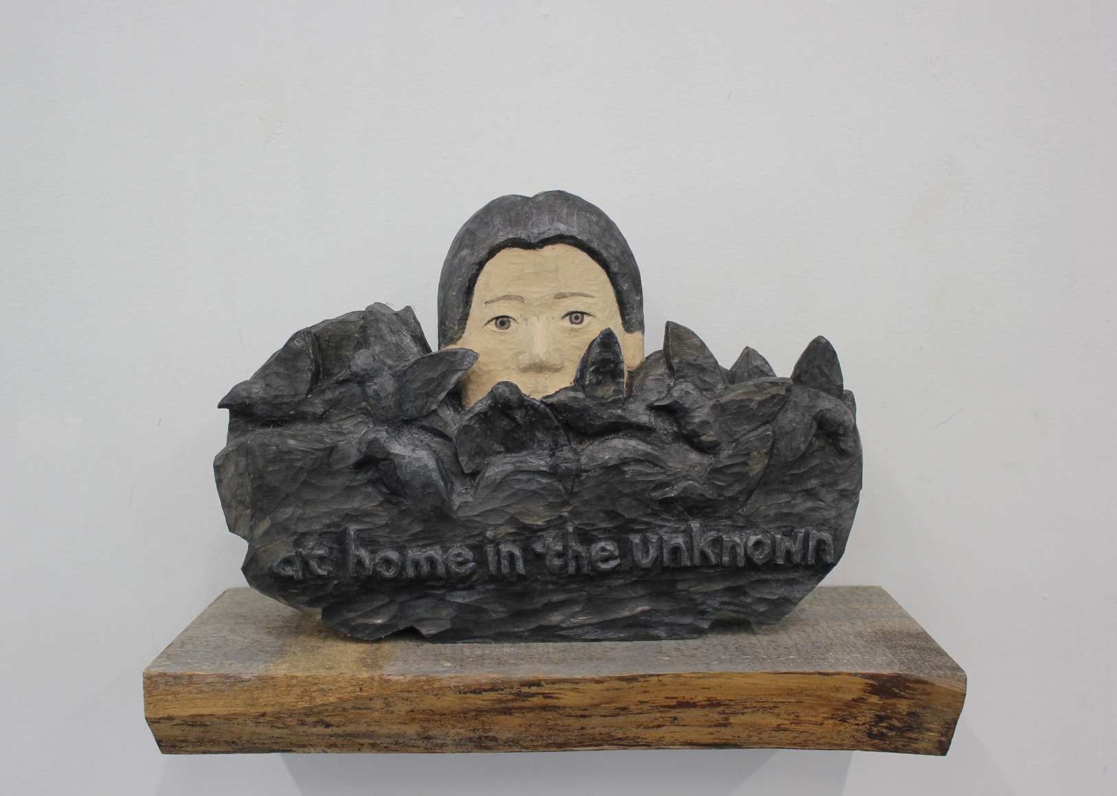 Wooden sculpture with head an text