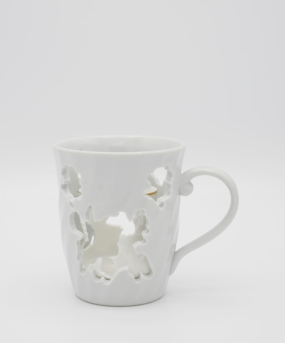 A white porcelain tea cup with hand cut patterns