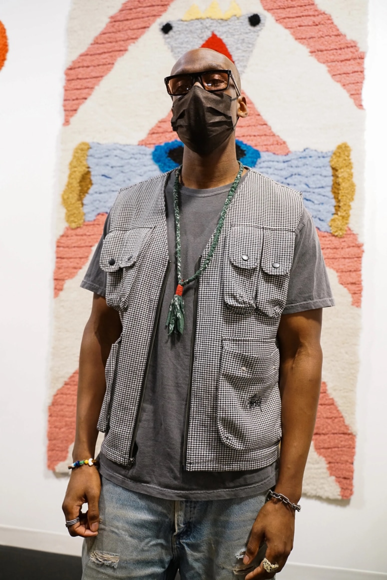 A visitor to the booth stands in front of Nick Weddell&#039;s Visitor&nbsp;(2021, wool, inquire for price)