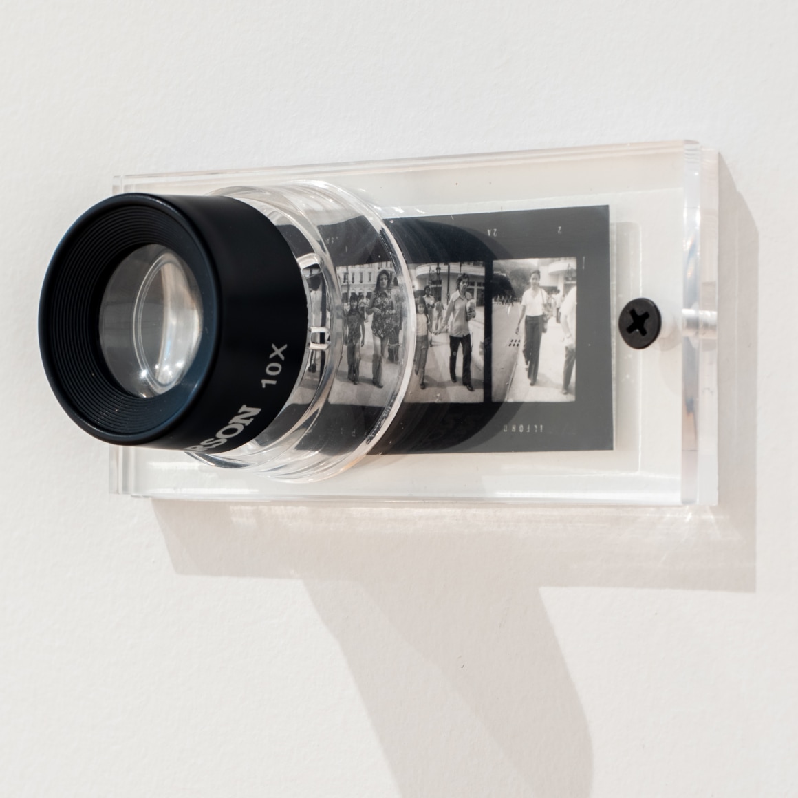 Oscar Mu&ntilde;oz, 3-3A, 2008. Magnifying glass and four contact negatives installed on wall, 1 5/8 x 4 3/8 in. (4 x 11 cm.)