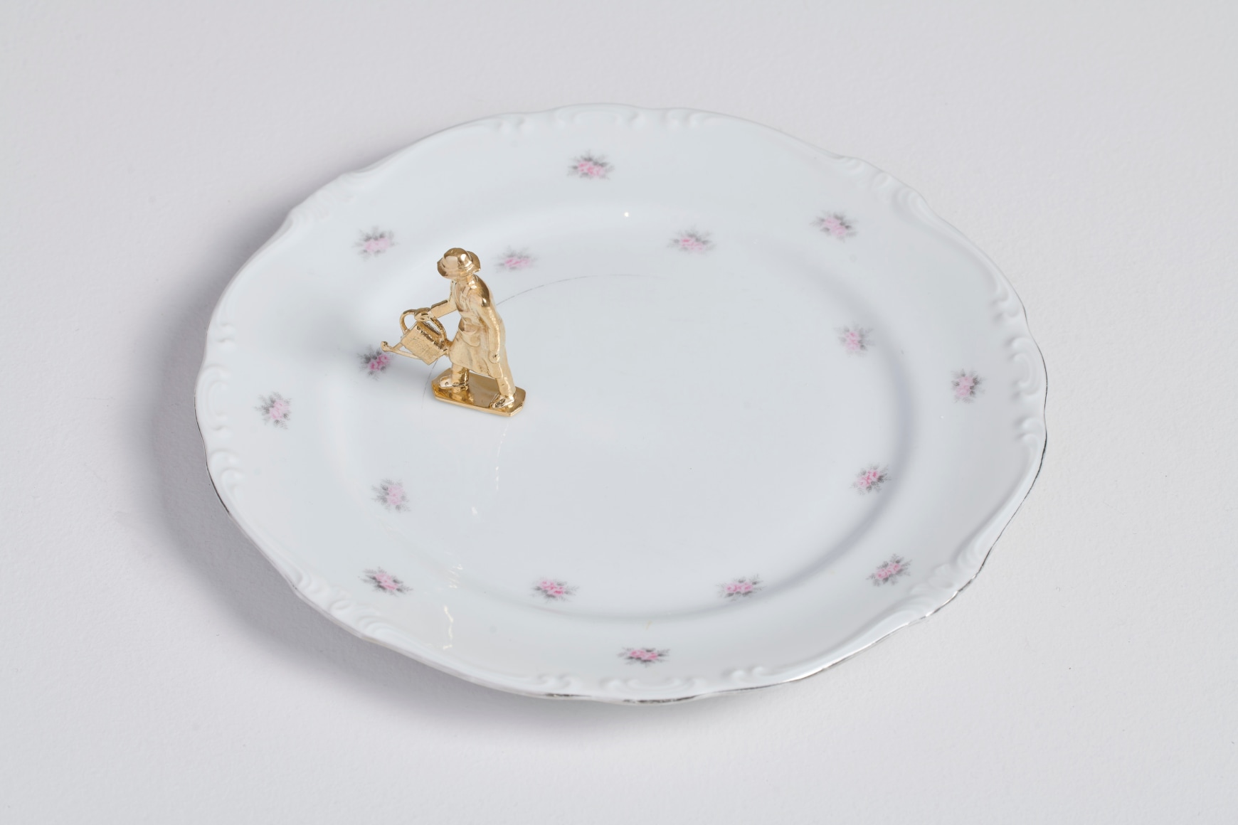 Liliana Porter, The Gardener (Pink Flowers), 2024. Bronze figure and plate, 3 &frac14; x 10 x 10 in. (8.3 x 25.4 x 25.4 cm.)