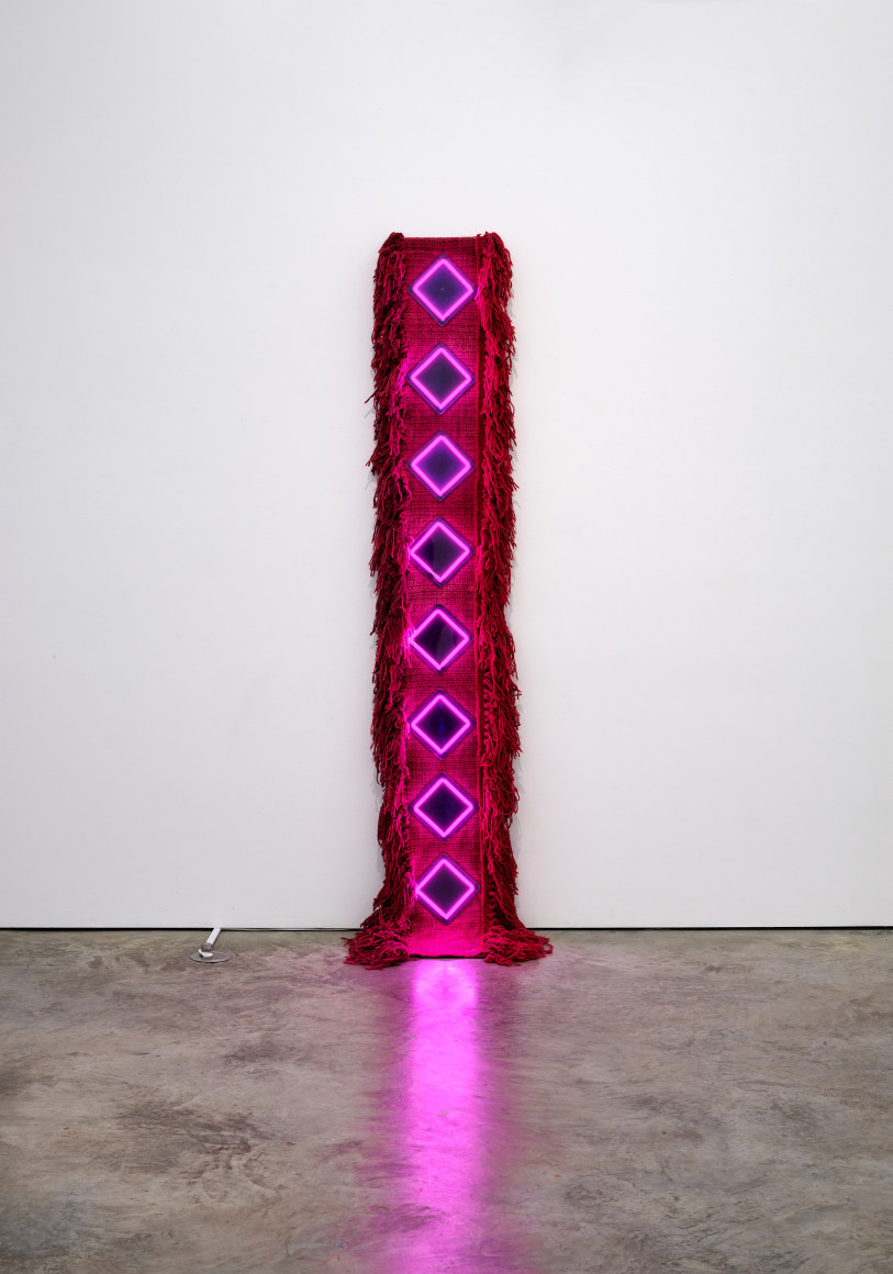 Sandra Monterroso, Como el rombo: la tierra y la cochinilla nos devuelven la luz [Like the rhombus: the earth and the cochineal give us back the light], 2022. Wool rug dyed with cochineal, cotton cloth dyed with indigo, acrylic, neon, 102 3/8 x 19 5/8 x 5 7/8 in. (260 x 50 x 15 cm.)