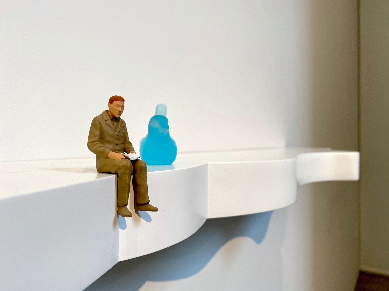 Liliana Porter, To Read, 2019. Glass bird and resin figurine on shelf, 43 x 10 1/2 x 4 in. (109.2 x 26.7 x 10.2 cm.) detail