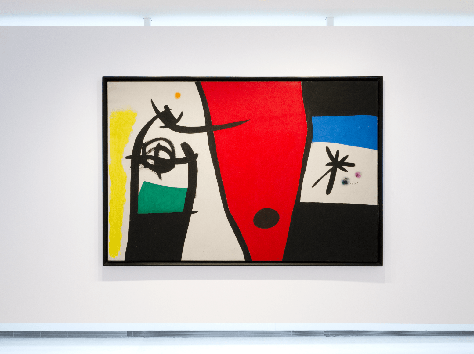 This is a photo of a large scale painting produced by Joan Miro titled &quot;Femme &agrave; la voix de rossignol dans la nuit&quot; and produced 1971. It is abstract and the rectangular horizontal canvas is composed of 3 ares each divided by a thick black line. The left side is depicting in a calligraphic brushstoke style executed with thick black line a shape that looks like the top part of a large fish, revealing a head and an eye. Theres a rectangular dark green area under that animal like form on the left of it is an area painting in bright yellow. On the right of that form is the center of the canvas shaped as a wide red cone shape with a large black dot at its bottom. On the right of the canvas, the area is divided in four very wide stripes piled up horizontally, the first stripe is black, the second underneath is a rich blue azure, underneath is the raw canvas not painted with the motif of a large star executed with thick black lines there is two dots on the right of it, one green, one purple. underneath there is a black stripe.